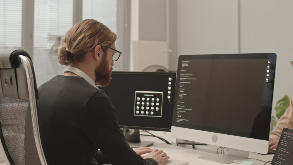 Arbeitsplatz mit zwei Bildschirmen und Programmcode